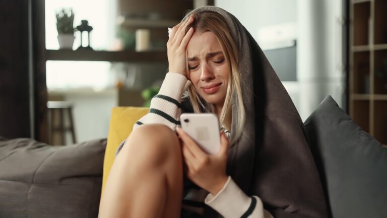 Portrait,Of,Crying,Young,Blond,Woman,With,Smartphone,Sitting,On