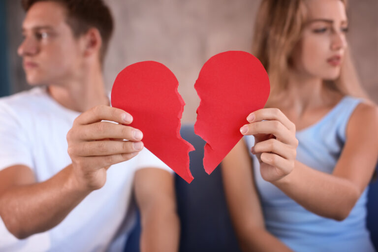 Young,Couple,Holding,Halves,Of,Broken,Heart,On,Sofa,At